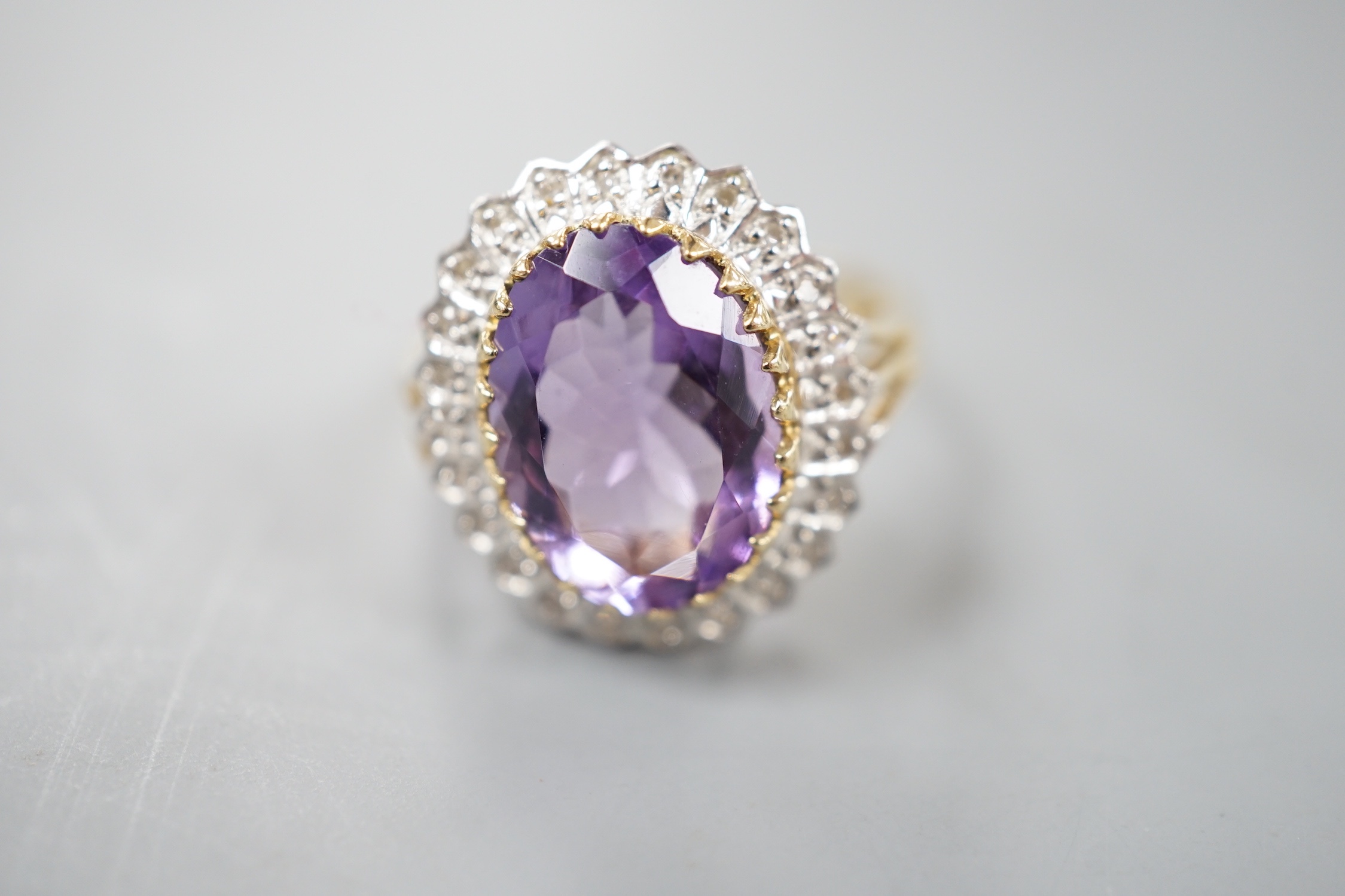 A modern 9ct gold, amethyst and diamond chip set oval cluster ring, size Q, gross weight 4.6 grams.